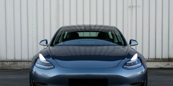 Front view of a sleek blue Tesla Model 3, received ceramic window tinting, ceramic coating, and paint protection film