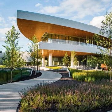 Modern building with curved architecture surrounded by greenery and a winding pathway.
