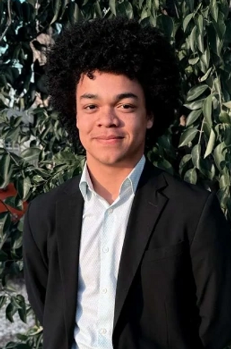 A young man with an afro in a suit running for office.