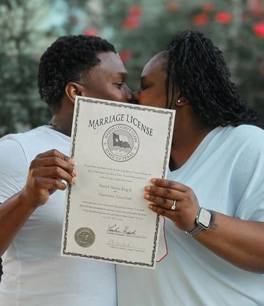 Couple kissing behind their marriage license, celebrating their union.