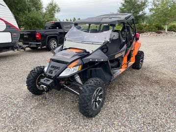 Orange and black off-road dune buggy parked on gravel.