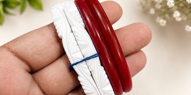Hand holding red and white bangles.