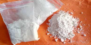 White powder in plastic bags and spilled on an orange surface.