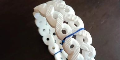 White infinity symbol bracelet with blue string detail.