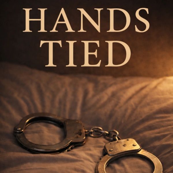 A pair of handcuffs on a bed with the words 'HANDS TIED' above.
