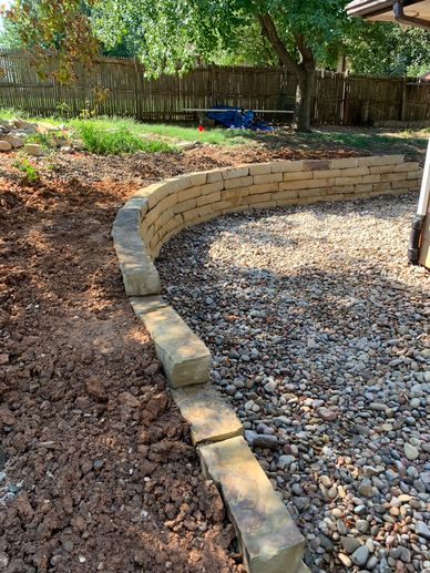 Curved stone retaining wall with gravel and soil.