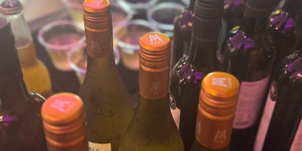 Close-up of bottles with orange caps and cups in the background.