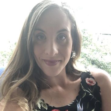 Woman with long hair smiling, wearing floral dress.