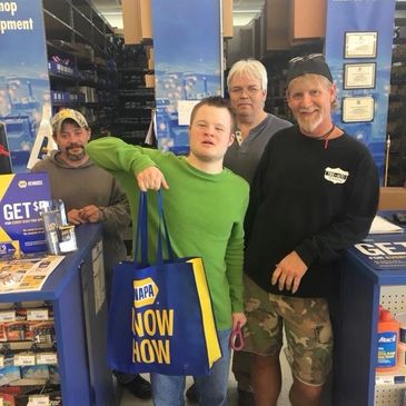 A man with down syndrome standing with silent auction donors from NAPA auto parts.