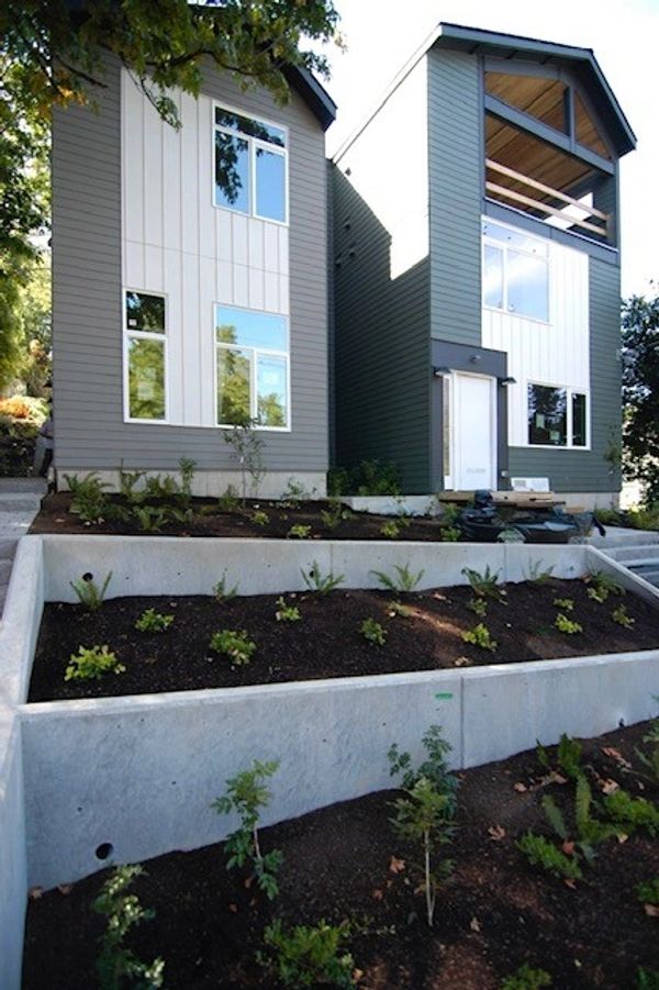 Two modern houses with tiered garden beds in front.