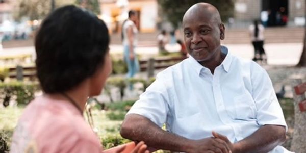 coach on bench in a park, talking to female client.