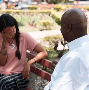 Coach talking to a woman on a bench in a park, consoling her.