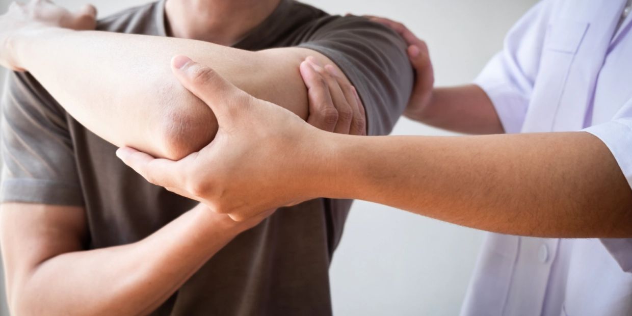 Physical therapist helping with elbow stretch.