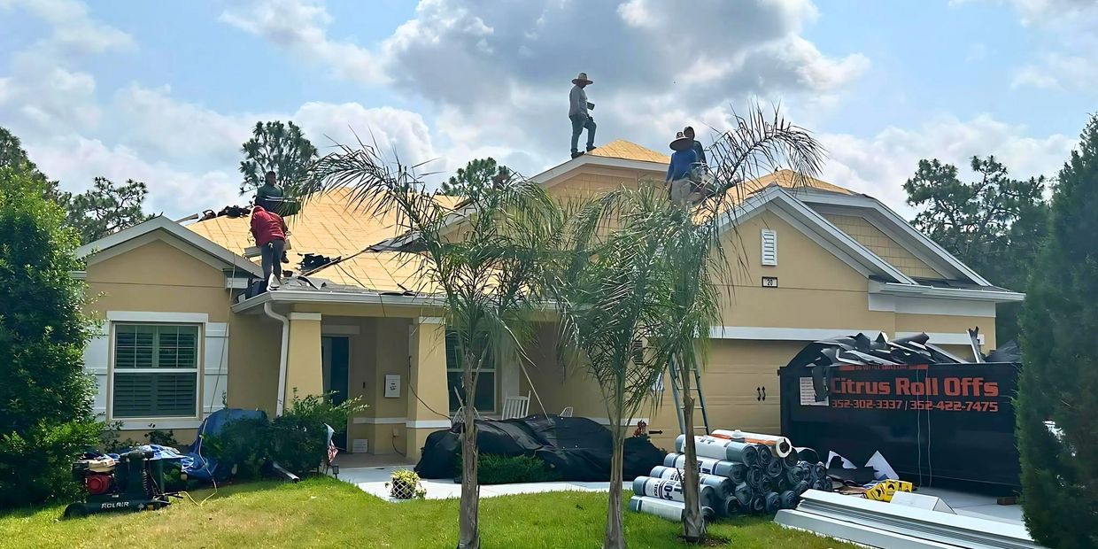 Workers repairing the roof of a yellow house working for FAS Roofing serving Inverness, FL