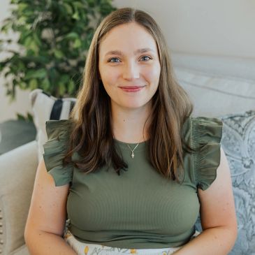 Smiling woman in green top sitting on a couch.