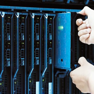 Hands installing or removing a server hard drive in a data center rack.