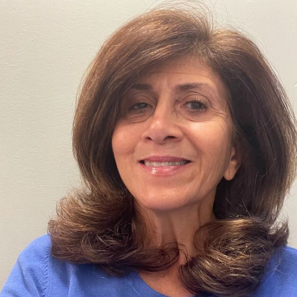 Smiling woman with voluminous brown hair and a blue top.