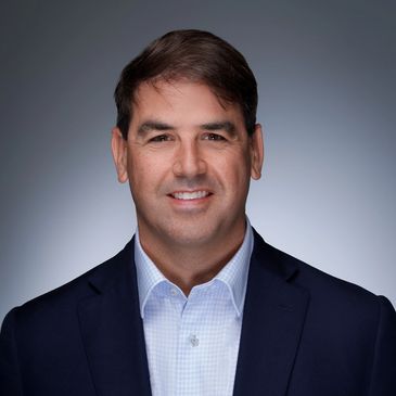 Professional headshot of a man in a dark suit jacket and light shirt.