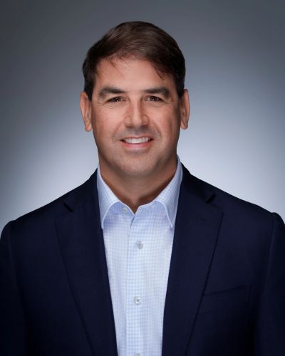 Professional man in a suit smiling against a gray background.