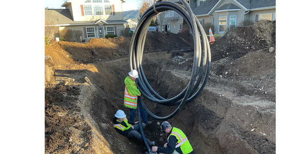Workers install underground pipes in a residential construction site.