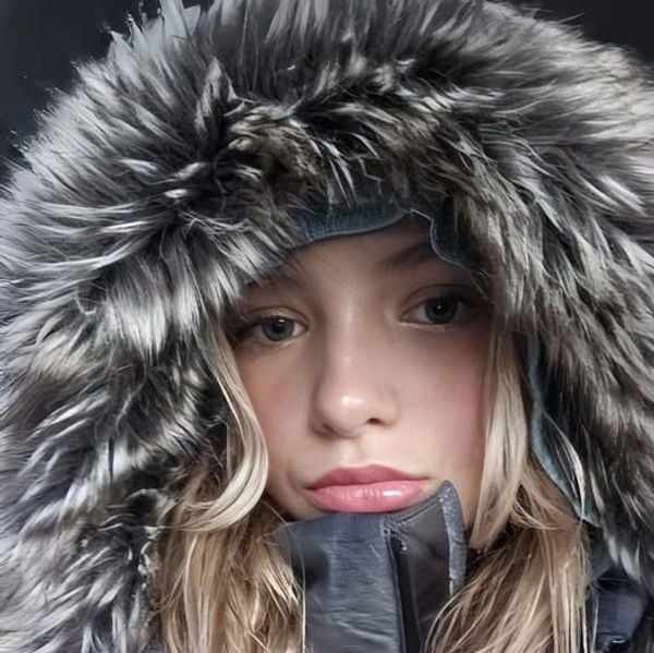 Young woman wearing a thick fur-lined hooded jacket.