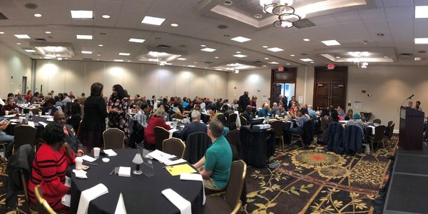 Large group attending a conference in a hotel ballroom.