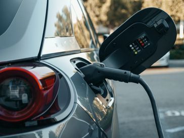 Electric car charging at a station with cable connected.