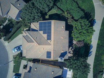 Aerial view of a residential house with solar panels on the roof.