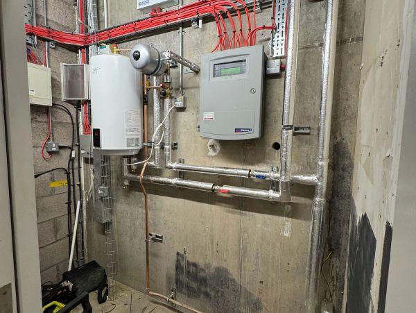 Boiler and piping setup in a utility room.