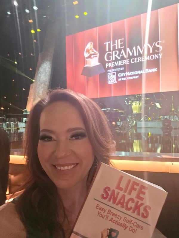 Catryn Becker at the GRAMMYS music awards, holding her book. Life Snacks.