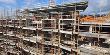 A multi-story building under construction with scaffolding and a crane.