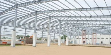 Under-construction large steel frame warehouse with concrete pillars.