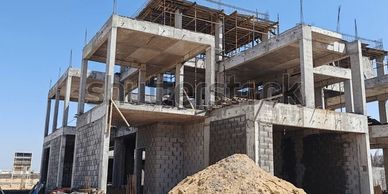 Concrete building under construction with clear blue sky.