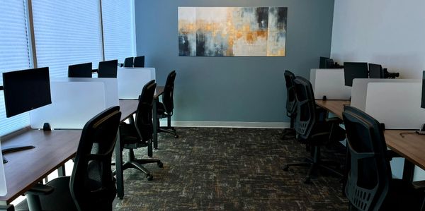 Coworking room with multiple desk and chairs. Dual monitors at each desk. 