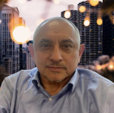 Man in a blue shirt with cityscape and lights background.