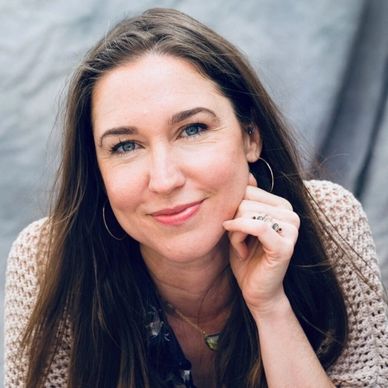 Smiling woman with long brown hair and hoop earrings.