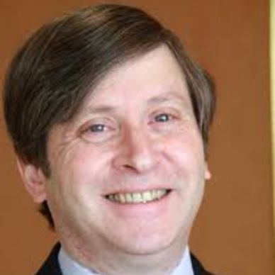 Smiling middle-aged man with brown hair in professional attire.