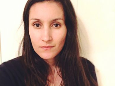 Portrait of a woman with long dark hair and a neutral expression.