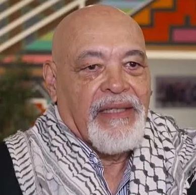 Older man with a white beard wearing a patterned scarf.