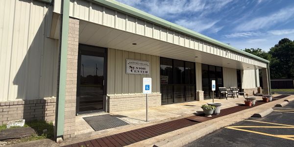 Exterior view of a senior center building with wheelchair accessible signs and seating area.