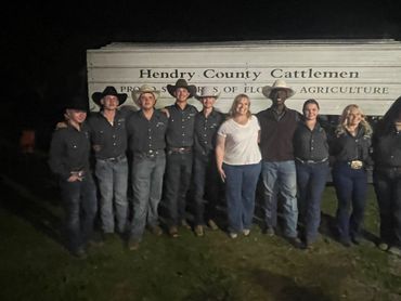 Group standing in front of Hendry County Cattlemen trailer at night.