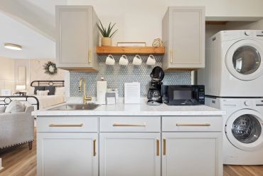 Modern kitchen with white cabinets and stacked washer and dryer.
