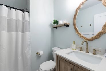 Modern bathroom with light blue walls and wooden accents.