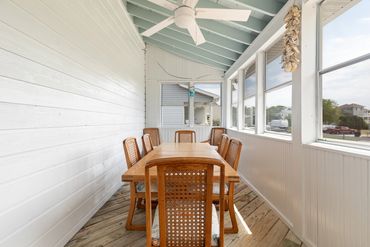 Cozy wooden porch dining area with large windows.