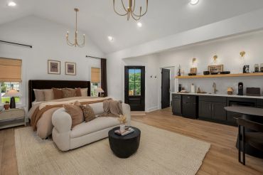 Stylish bedroom with cozy seating and modern kitchenette.