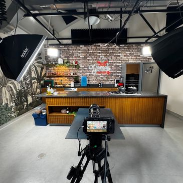 Professional studio kitchen setup with camera and lighting for filming.