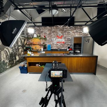 Professional studio kitchen setup with camera and lighting for filming.