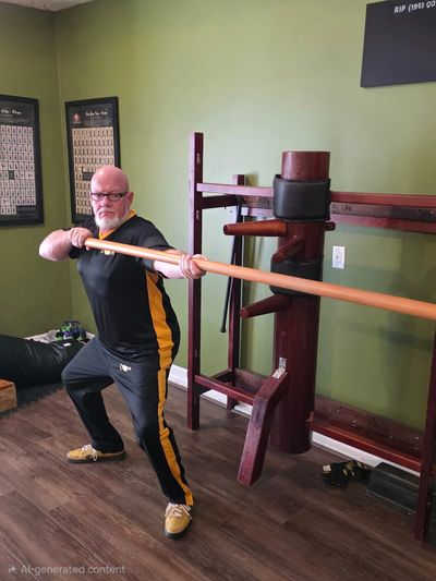 Man practicing martial arts with a wooden staff indoors.