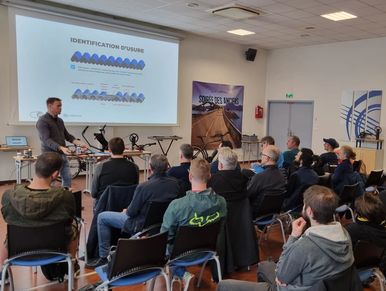 A presenter explains identification systems to an attentive audience in a conference room.