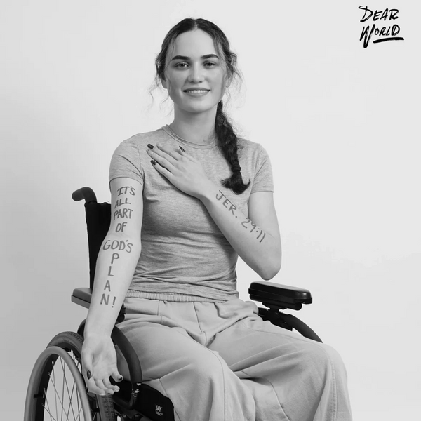 Young woman in a wheelchair with motivational text on her arms smiles.